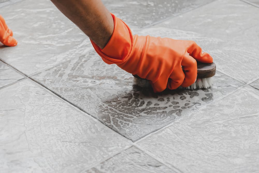 close up image of somebody scrubbing tile floor